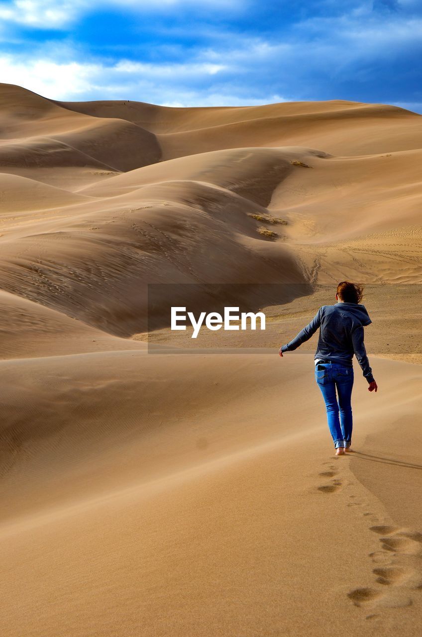 Full length of woman walking on sand dune