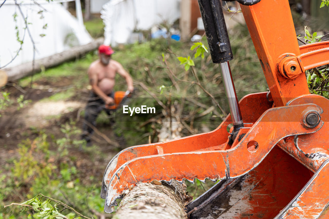 vehicle, nature, bicycle, plant, day, soil, mountain bike, chainsaw, orange color, focus on foreground, equipment, outdoors, occupation, working, mode of transportation, land vehicle, machinery, transportation