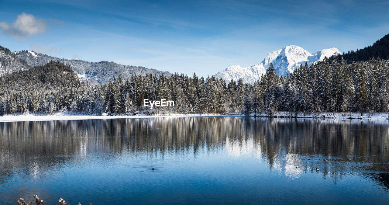 Scenic view of lake by snowcapped mountains against sky