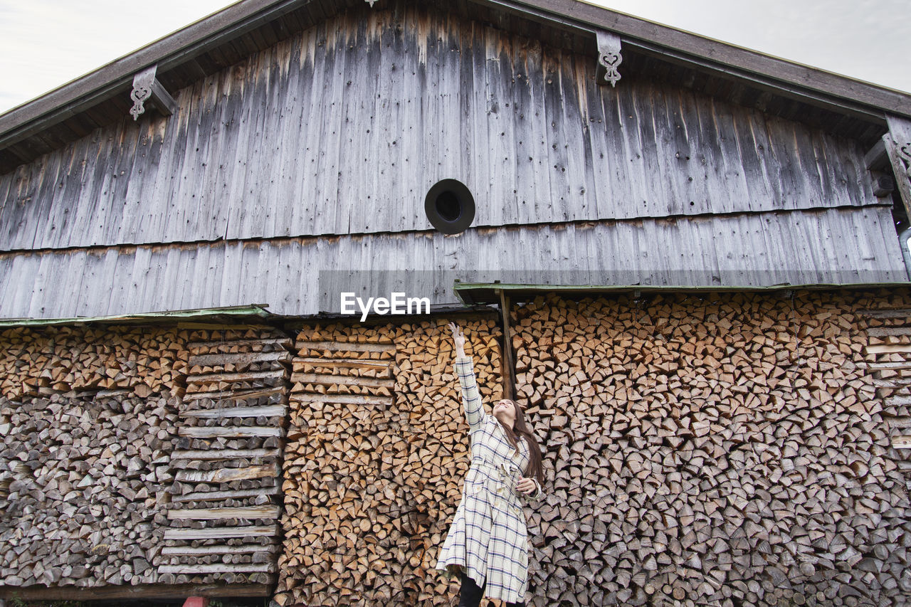 A young lady throwing her hat into the air by a wooden barn