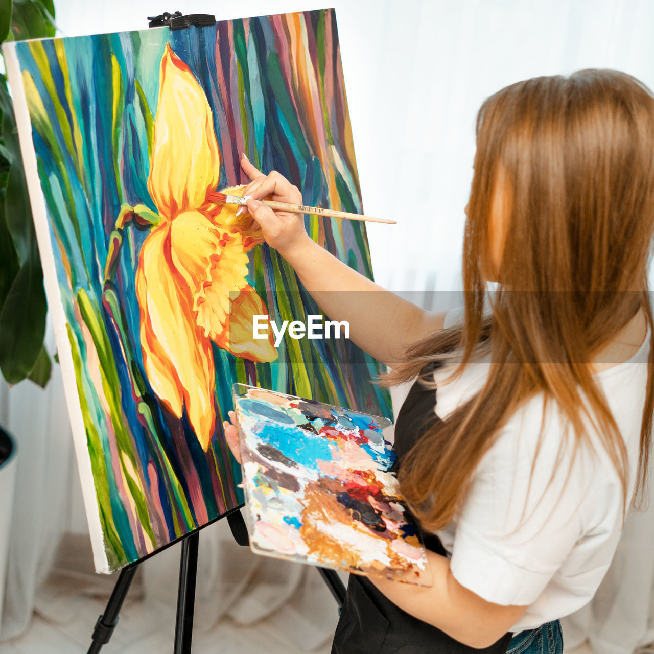 Side view of woman with long hair painting on canvas