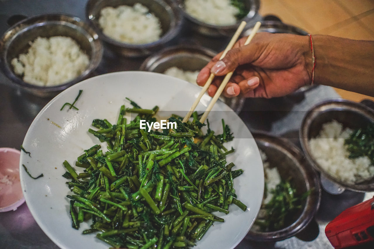 Cropped image of hand holding food in chopsticks