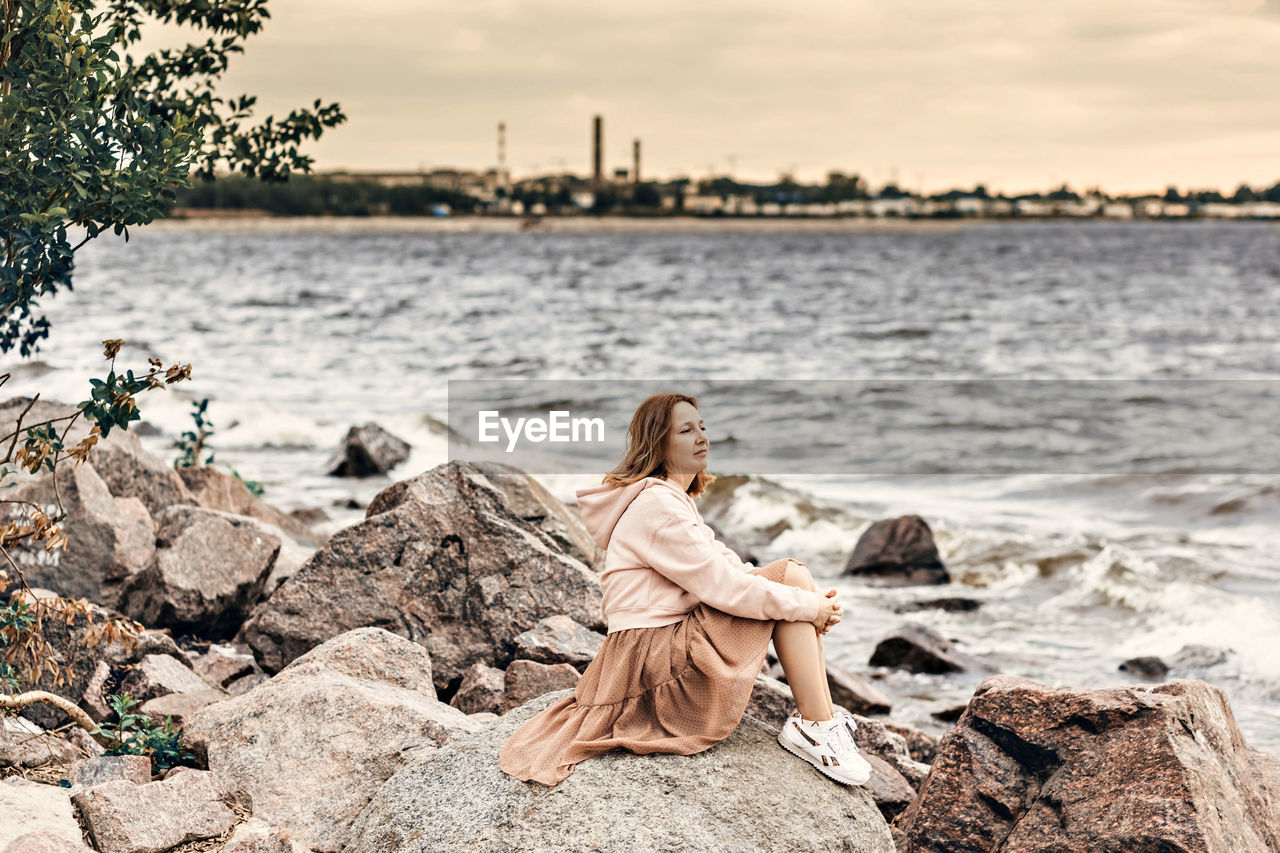 WOMAN SITTING ON ROCK IN WATER