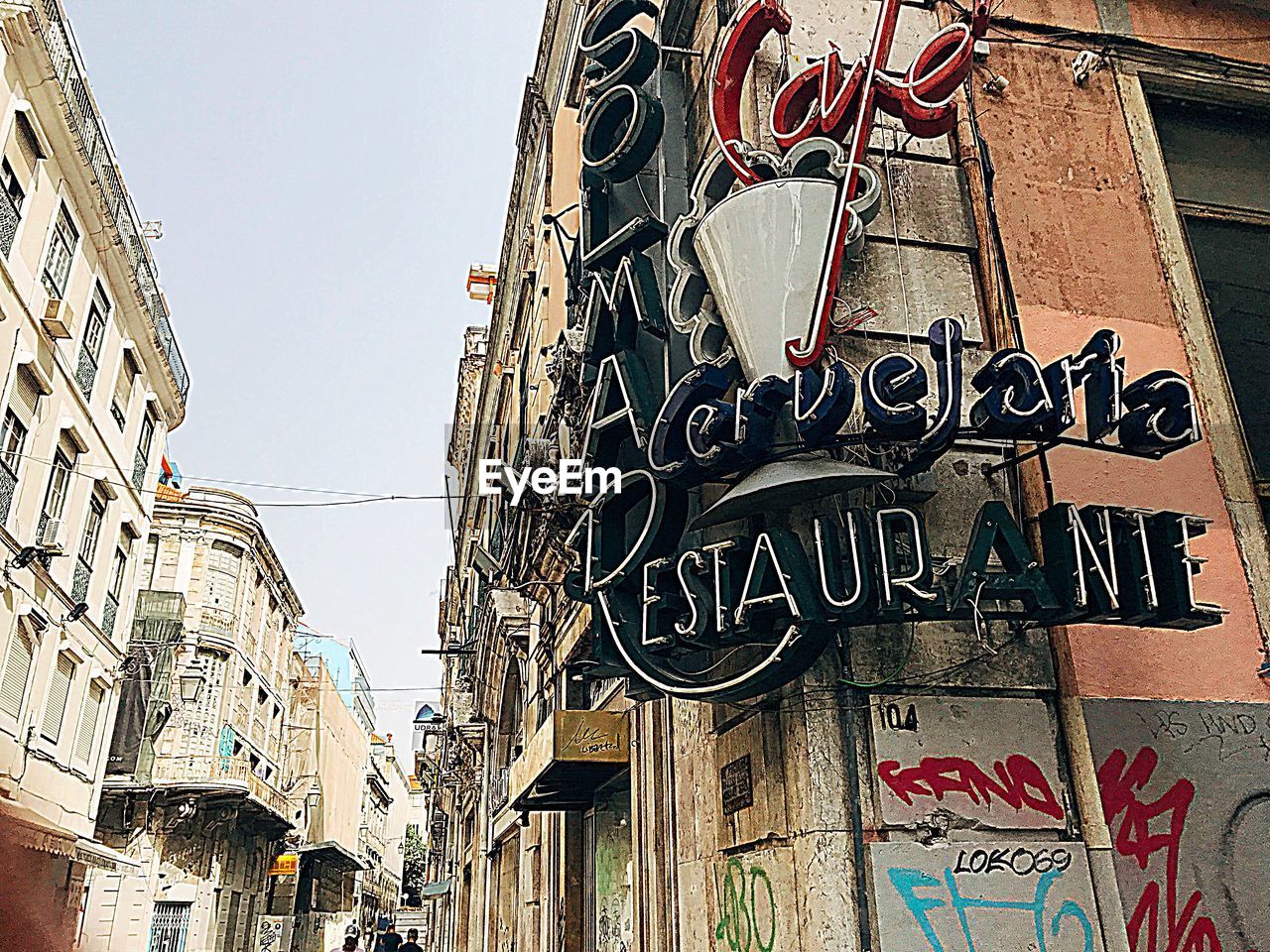 LOW ANGLE VIEW OF TEXT ON STREET AGAINST BUILDINGS