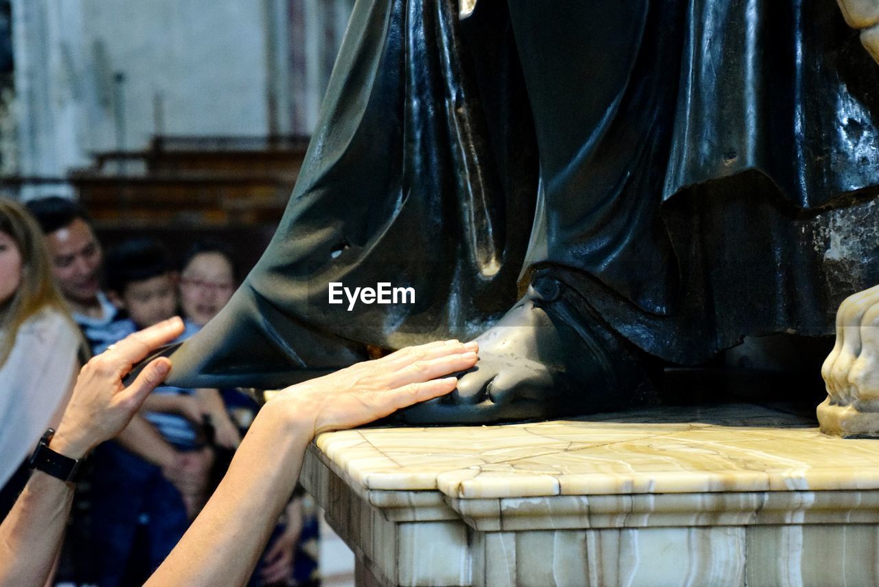 Cropped image of person touching statue