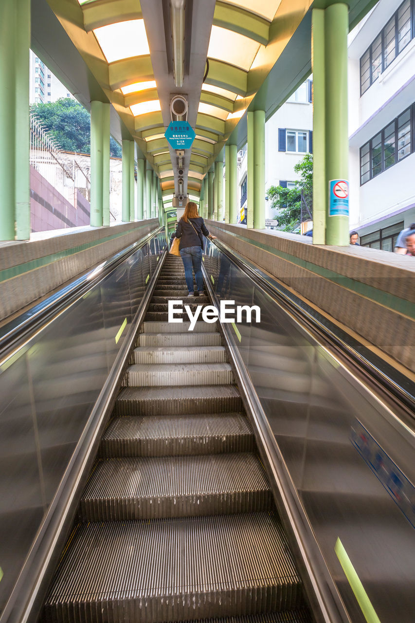 REAR VIEW OF MAN WALKING ON RAILWAY STATION PLATFORM