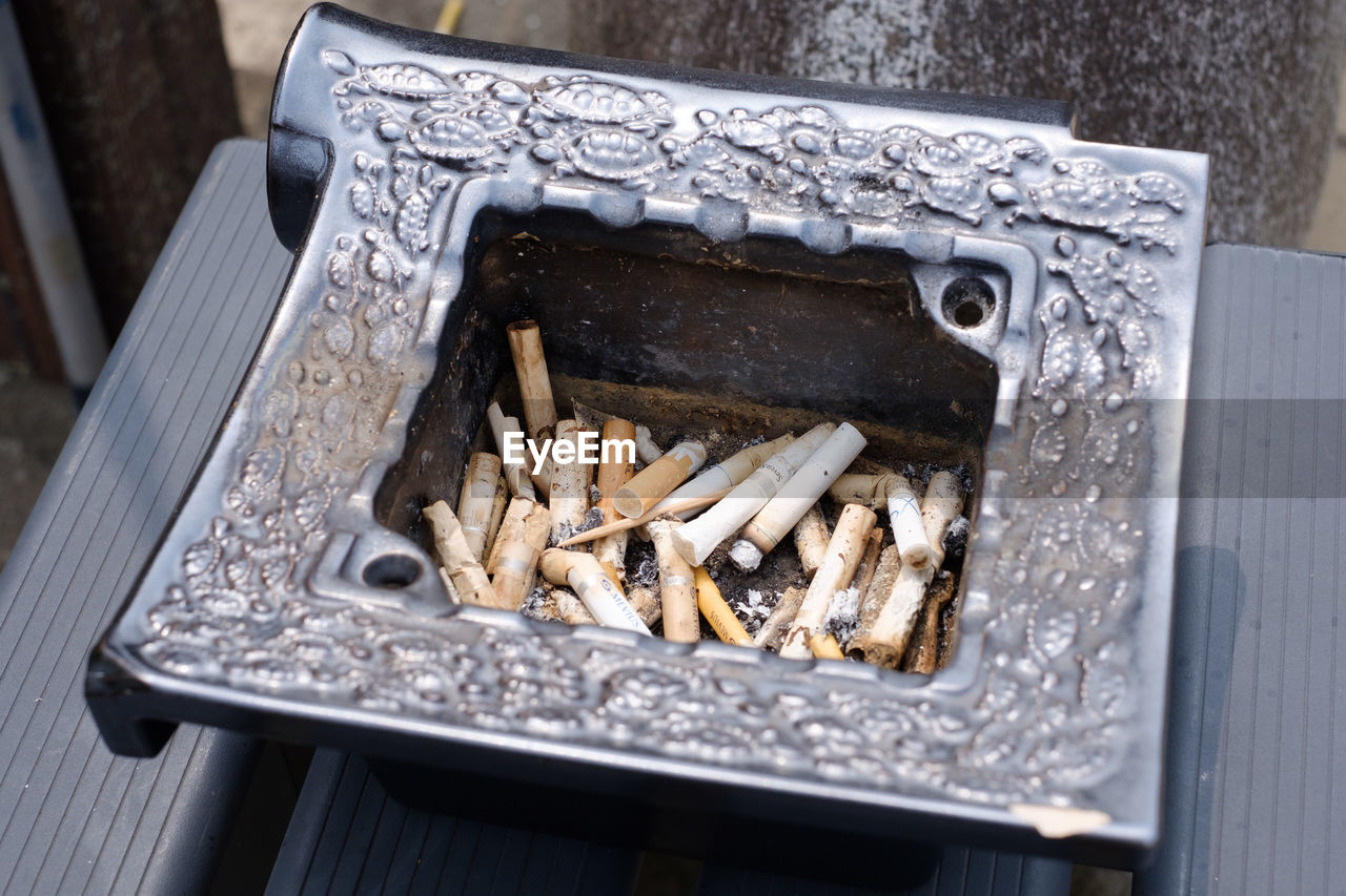 HIGH ANGLE VIEW OF CIGARETTE SMOKING ON METAL
