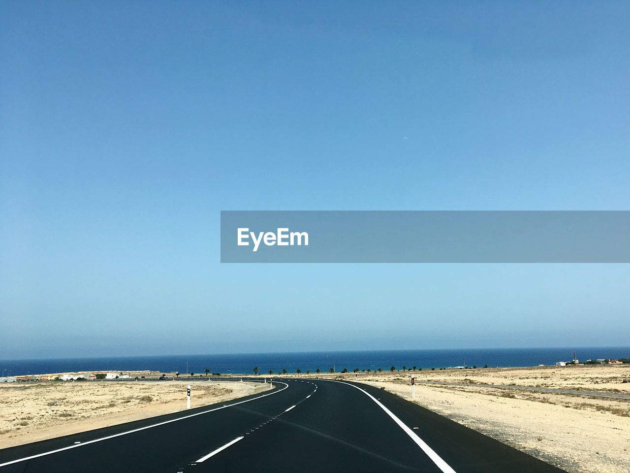 Empty road against clear blue sky