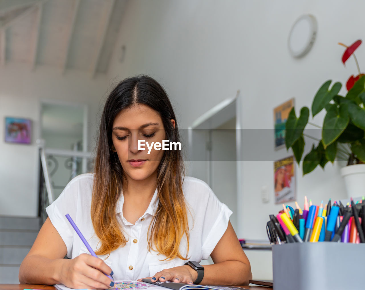 YOUNG WOMAN LOOKING AWAY WHILE SITTING IN TABLE