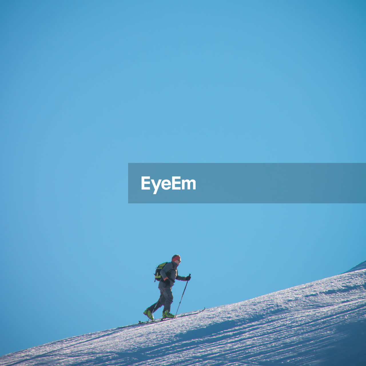 Low angle view of man walking on mountain against clear blue sky