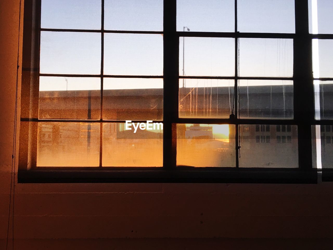 Low angle view of closed glass window against building during sunset