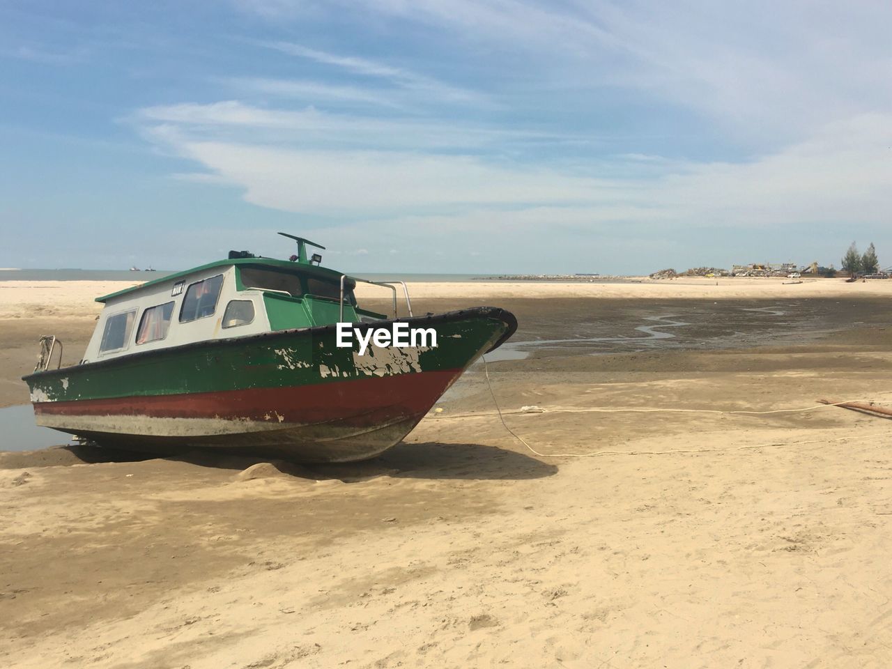 Boat moored on beach against sky