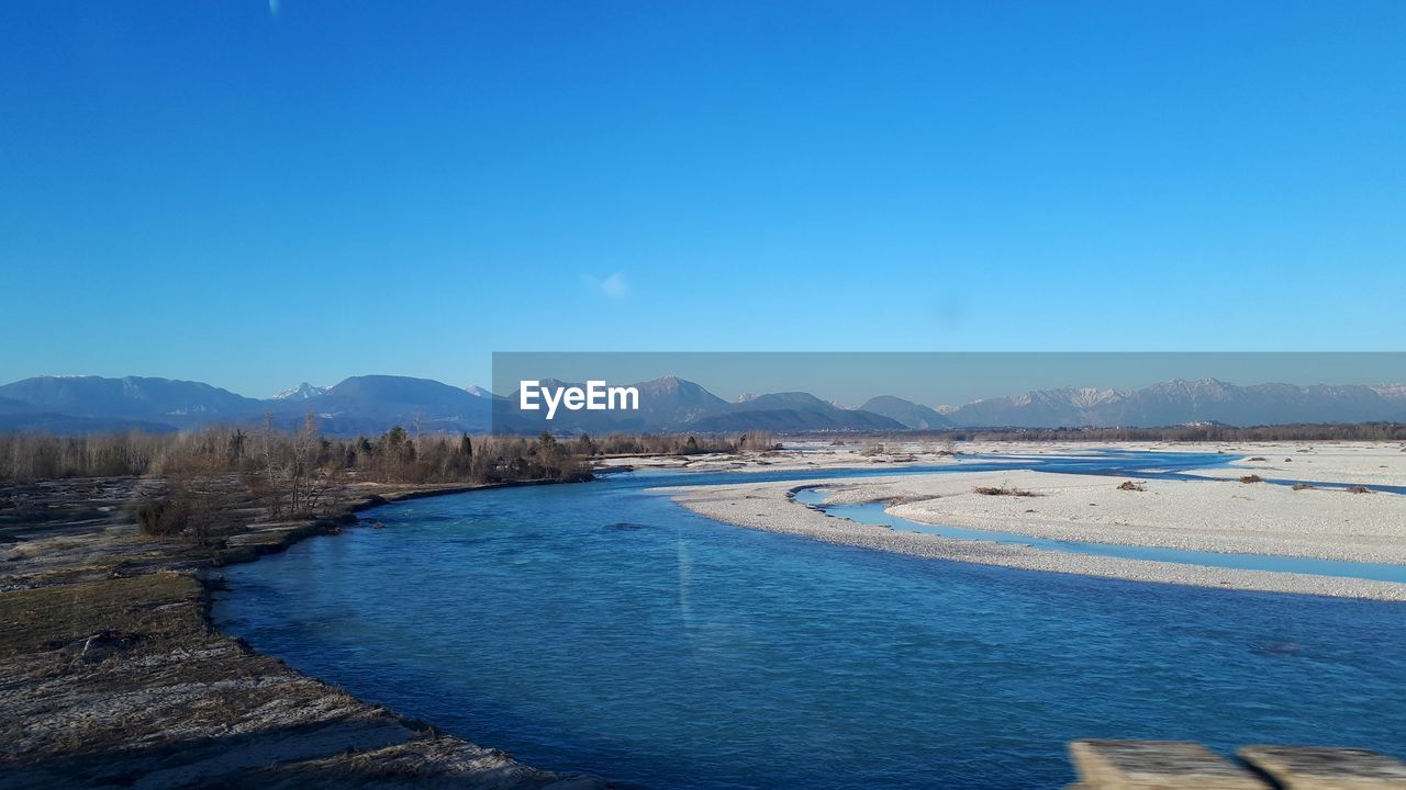 Scenic view of river against blue sky