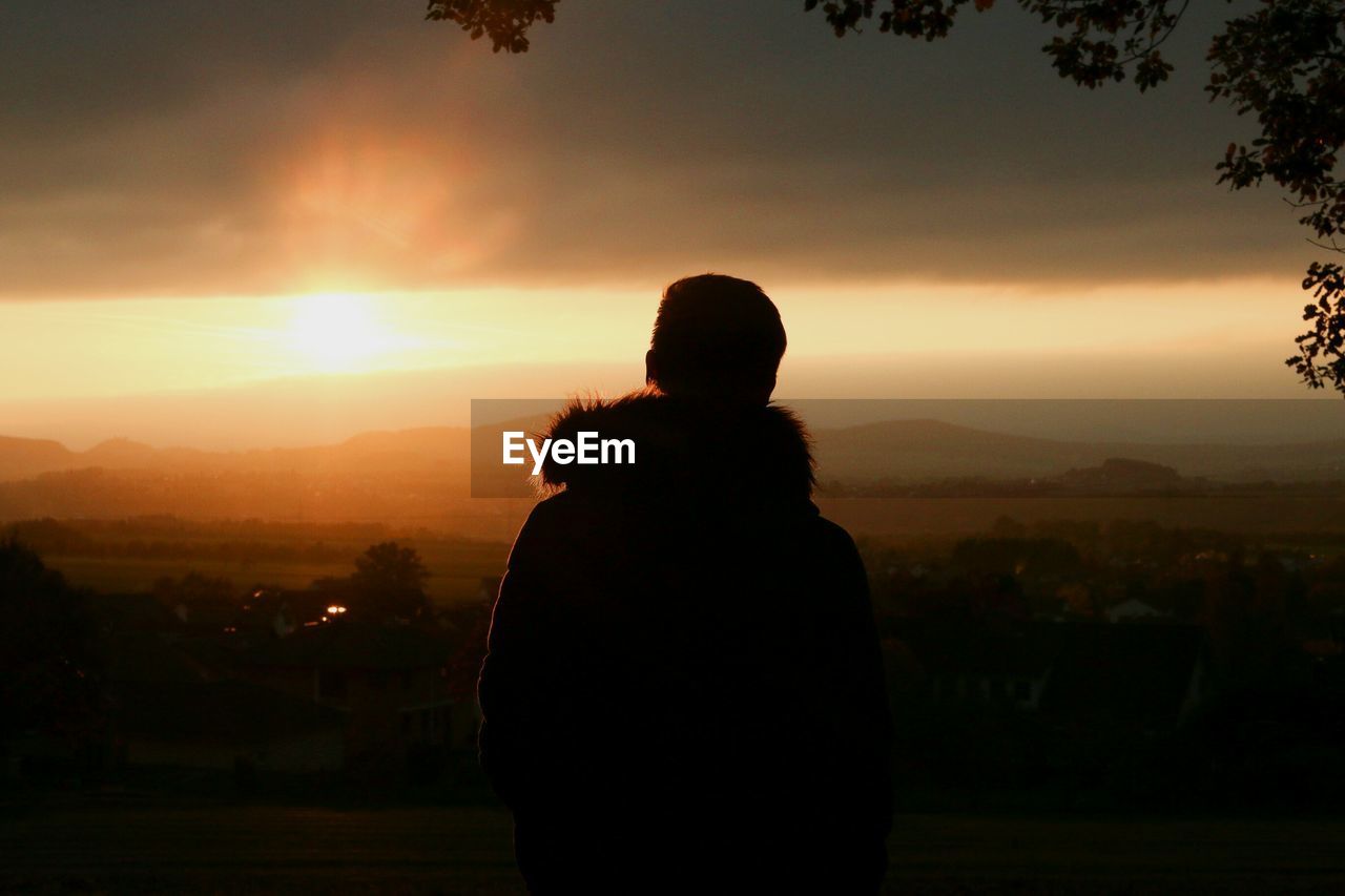 Rear view of silhouette man against sky during sunset