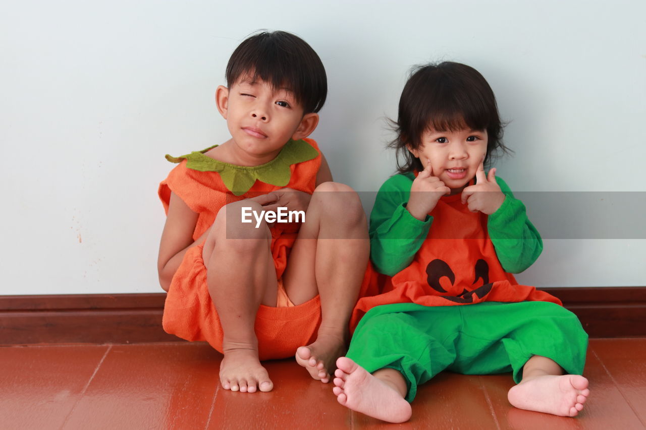 Portrait of cute kids sitting on floor at home
