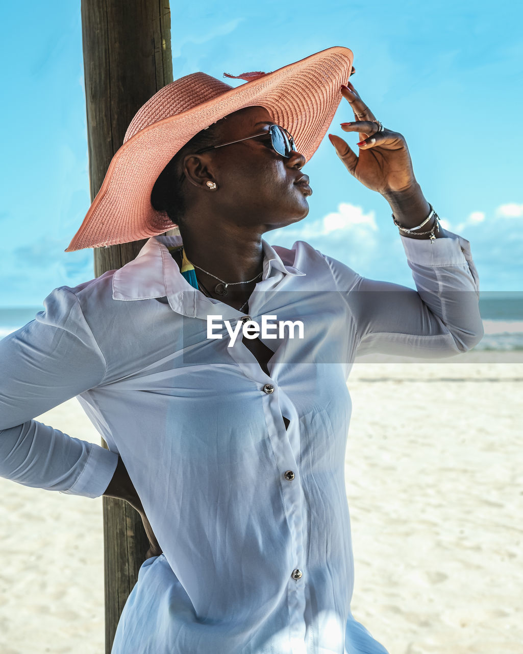 African woman standing in the shade with hat and sunglasses on the beach. bojo beach accra ghana 