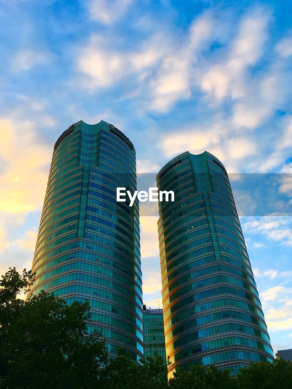 LOW ANGLE VIEW OF MODERN BUILDINGS AGAINST CLOUDY SKY