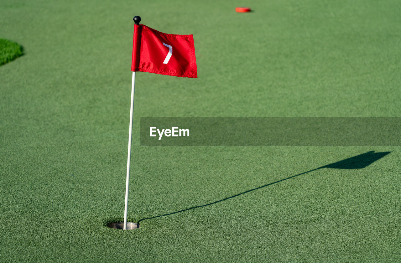 HIGH ANGLE VIEW OF RED BALL ON GREEN FLOOR