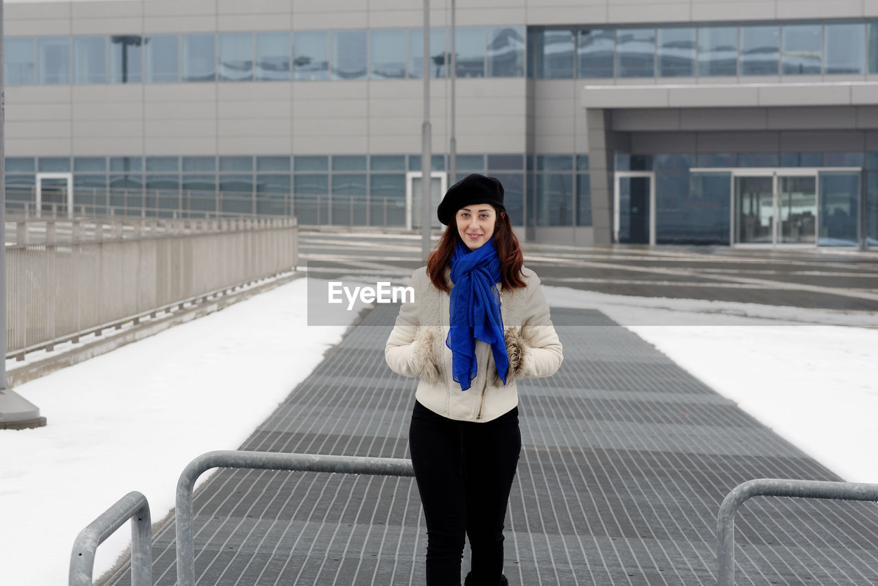 Full length of woman standing against railing in winter