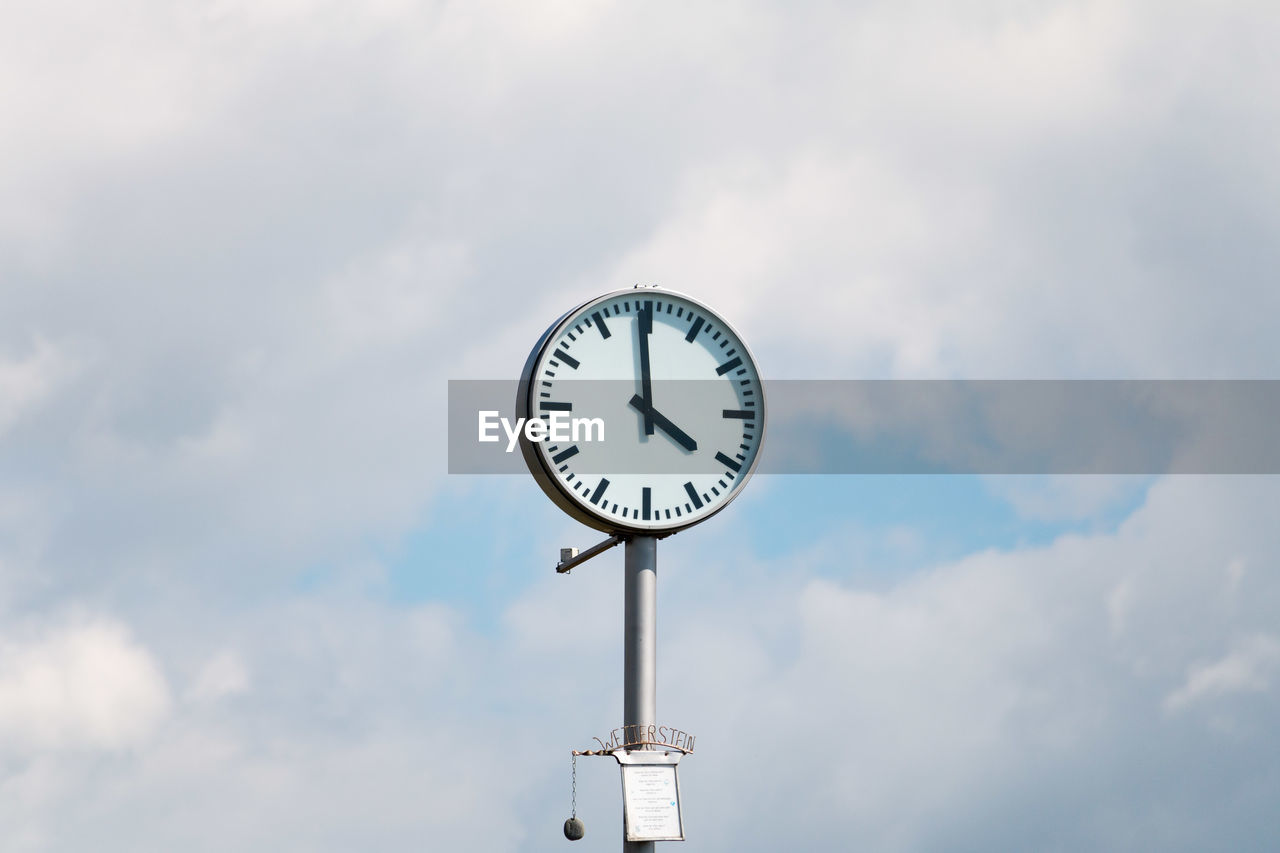 Low angle view of clock against sky