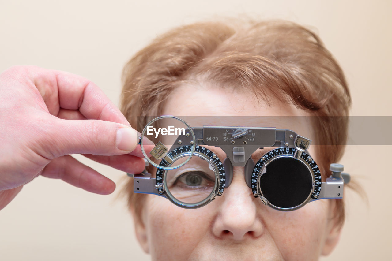 A male optometrist checks the eyesight of an adult woman with a trial frame