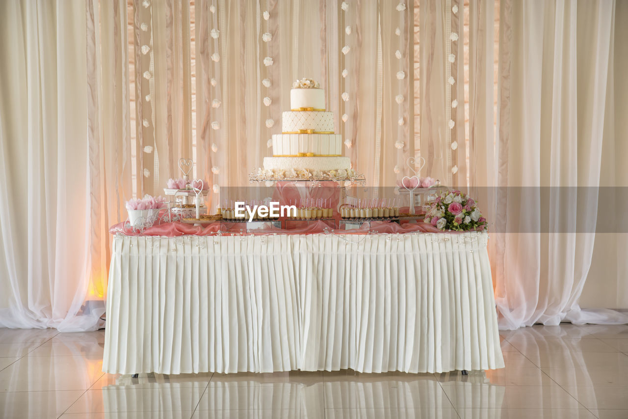 CLOSE-UP OF CAKE ON TABLE AGAINST CURTAIN