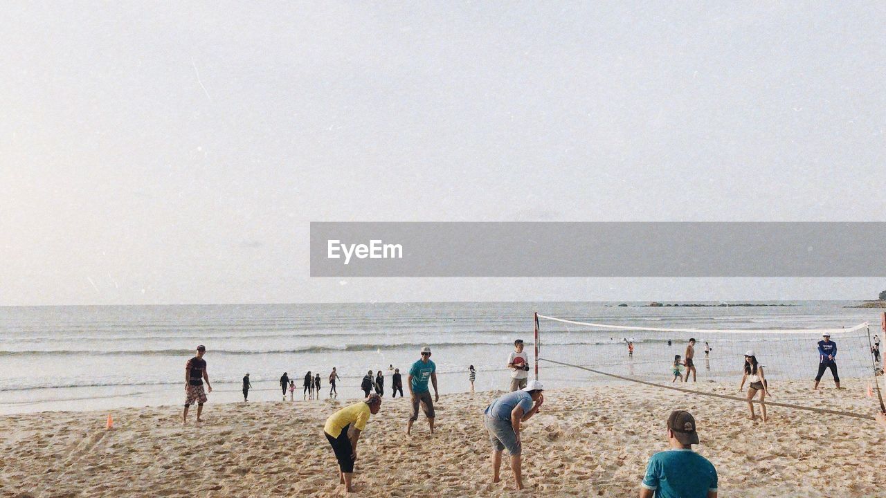 GROUP OF PEOPLE ON BEACH AGAINST SKY