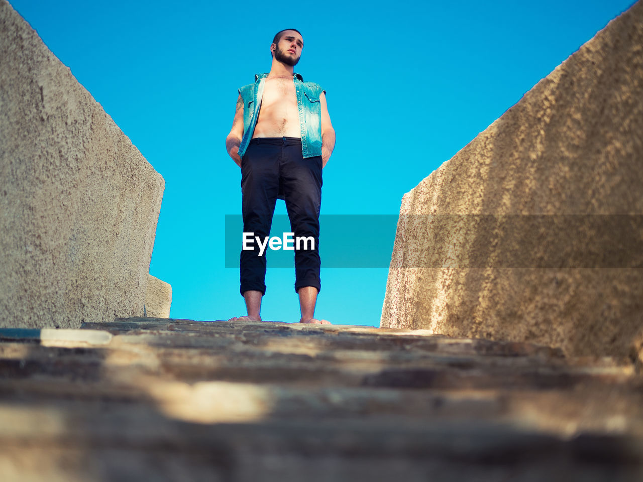 Low angle view of man standing on steps against clear blue sky