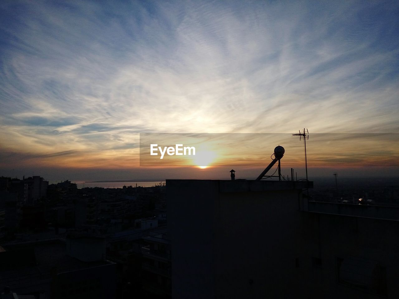 High angle view of silhouette buildings against cloudy sky