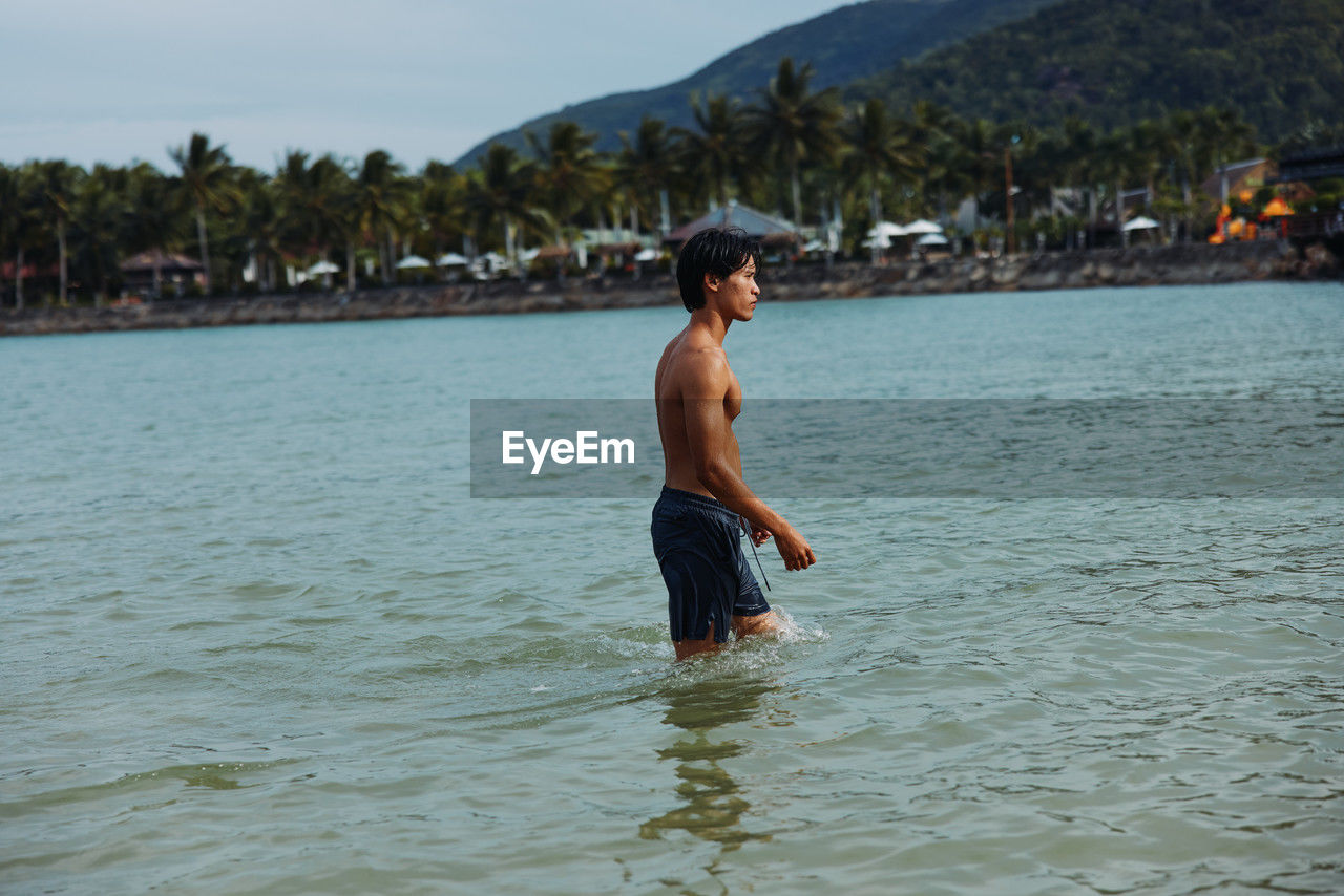 rear view of shirtless man standing in sea