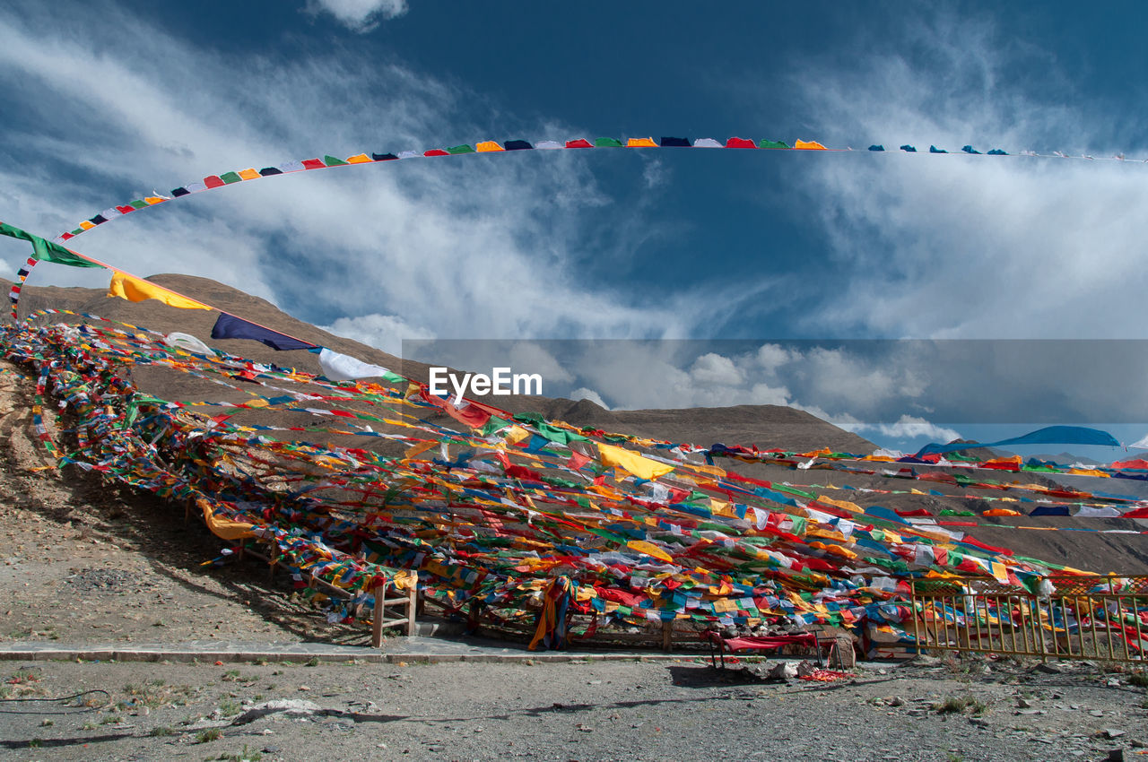 Multi colored flags hanging on mountain against sky