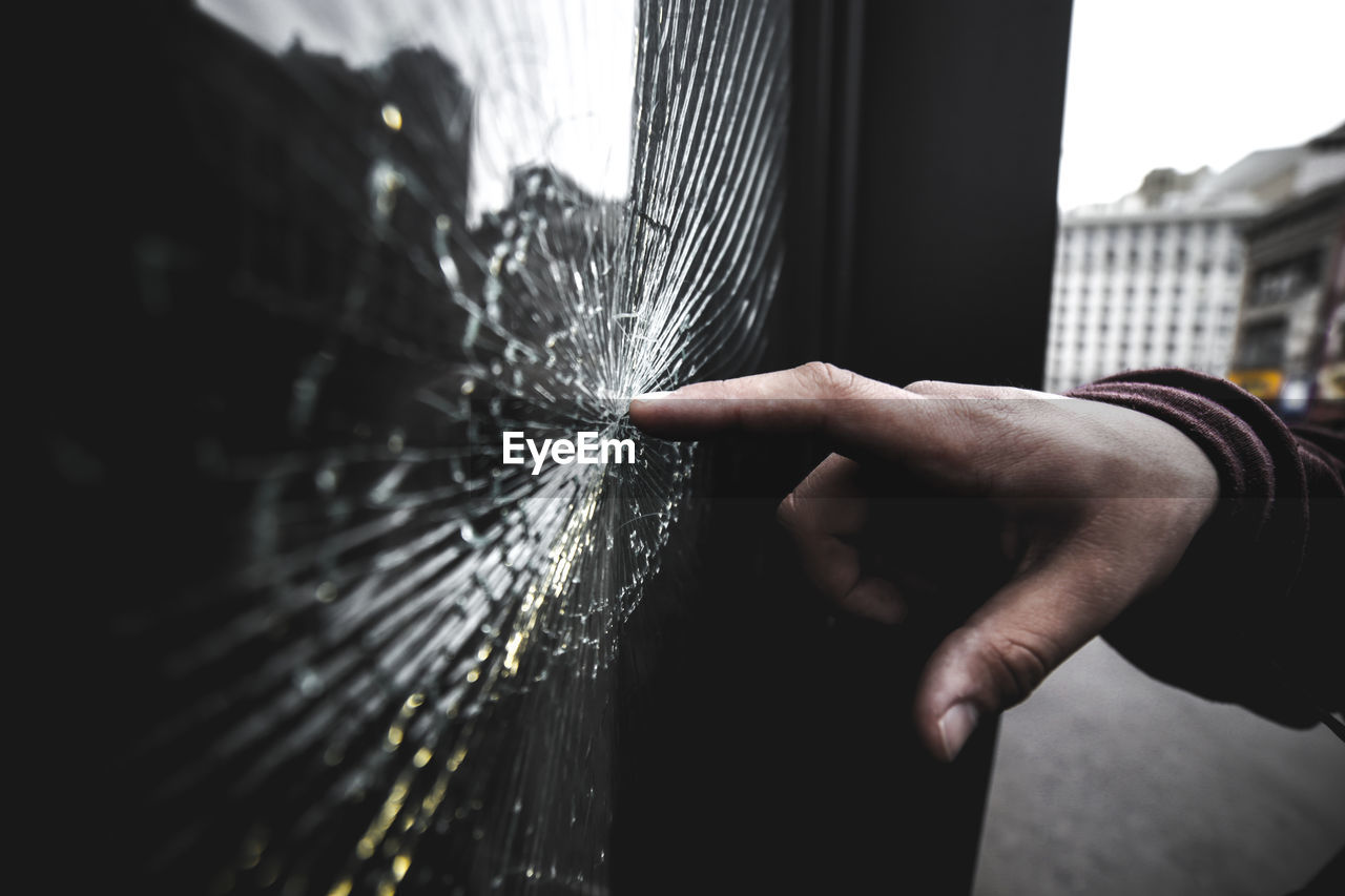 Close-up of hand on broken window