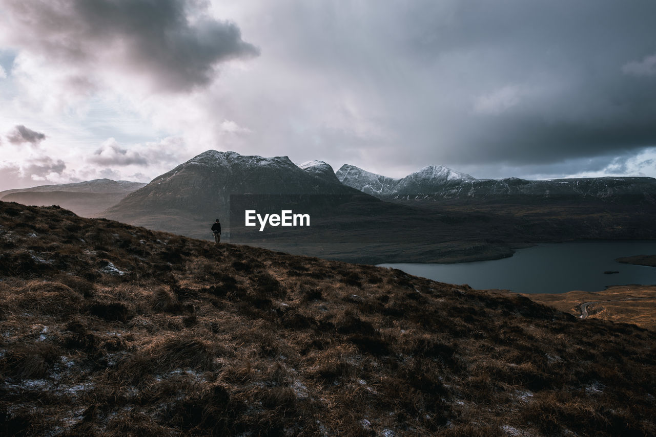 Person hiking on mountain by lake