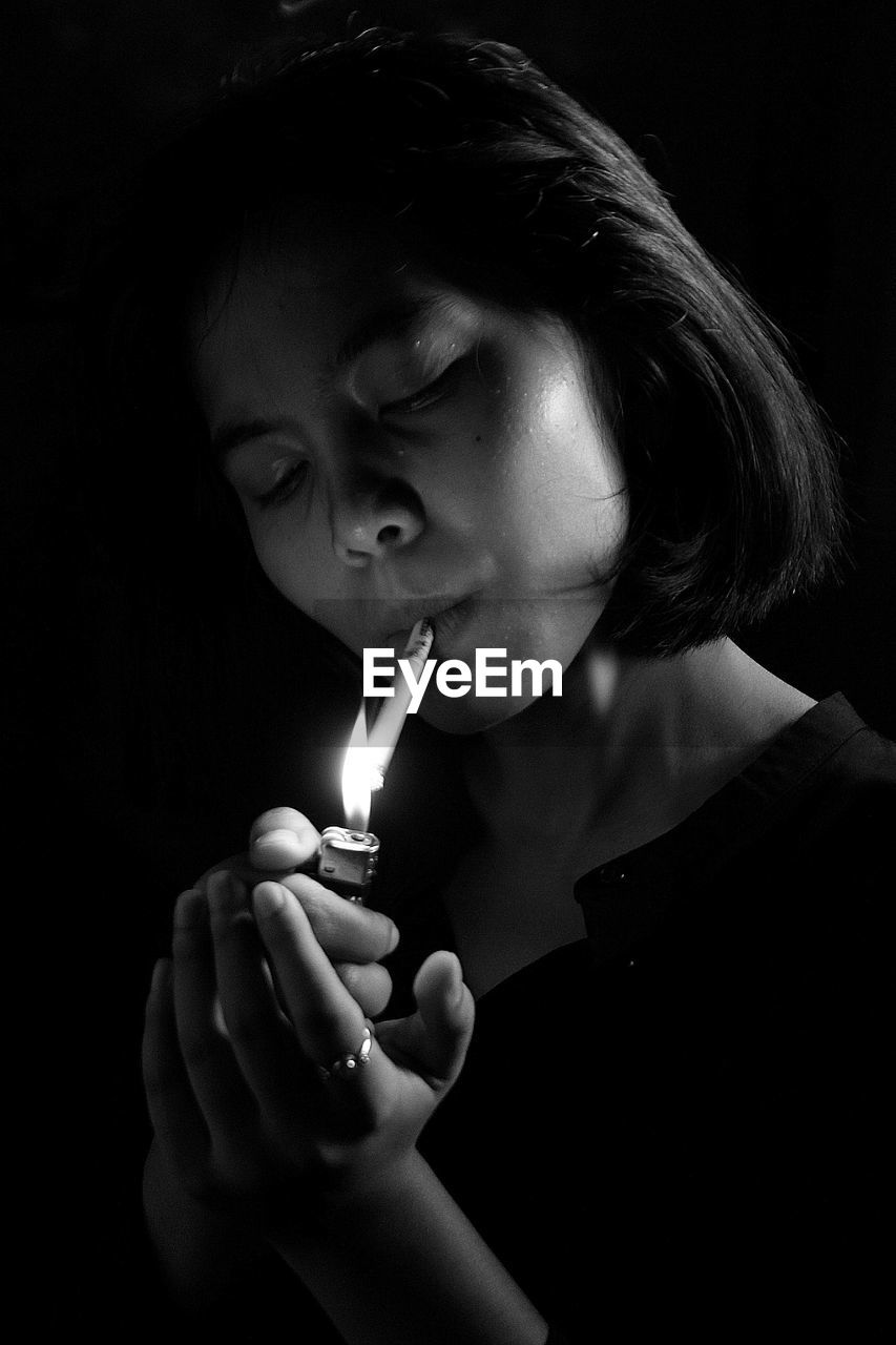 Close-up of woman lighting cigarette using lighter