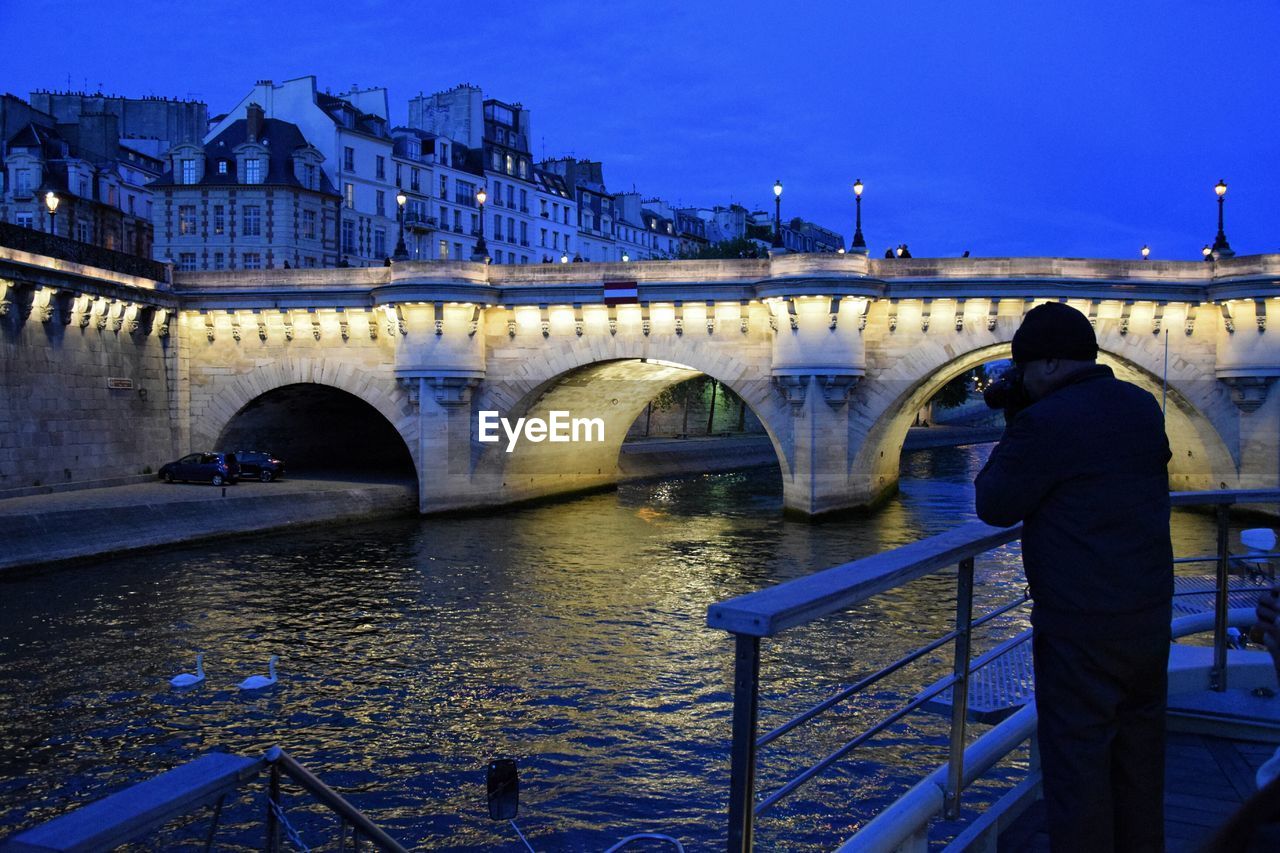 Illuminated bridge over river against clear sky at night