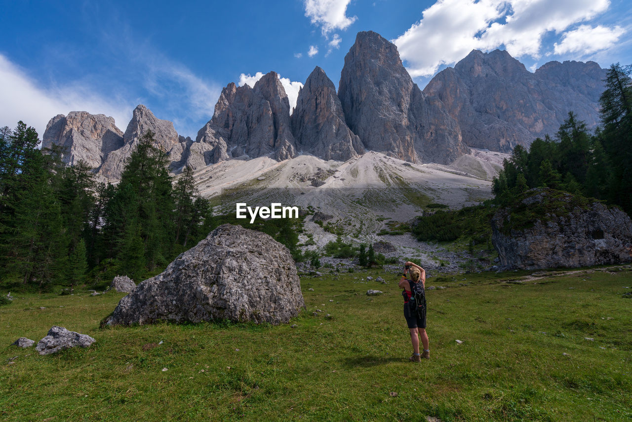 Rear view of woman standing on field against mountain range