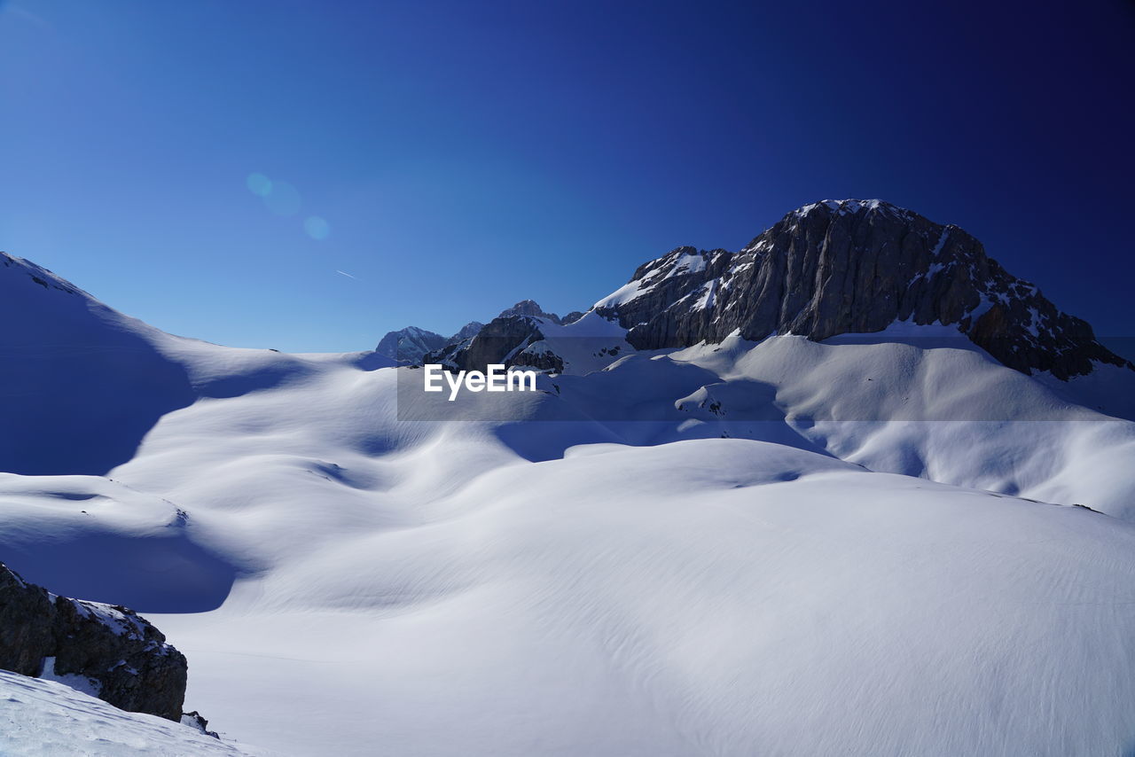 Scenic view of snowcapped mountains against blue sky