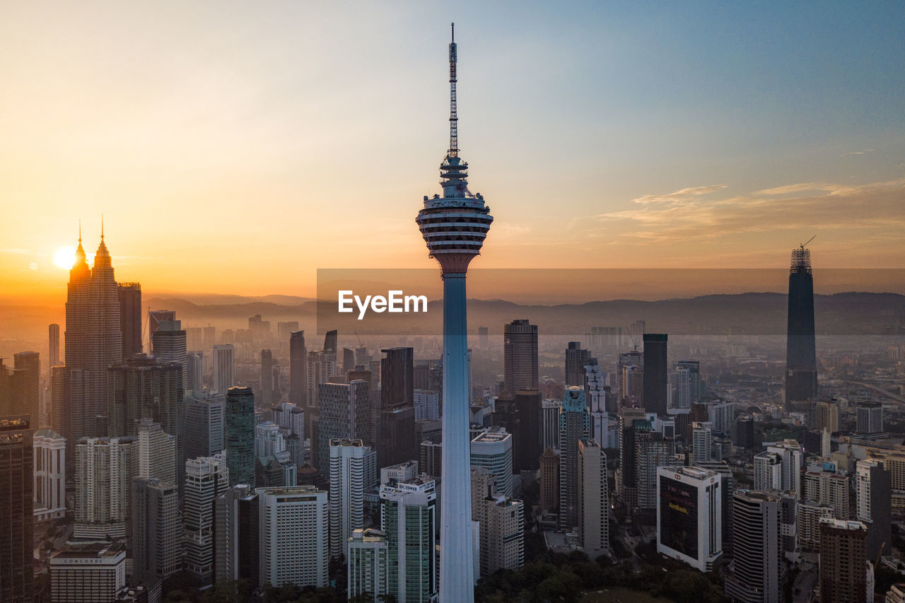 Modern buildings in city against sky during sunset