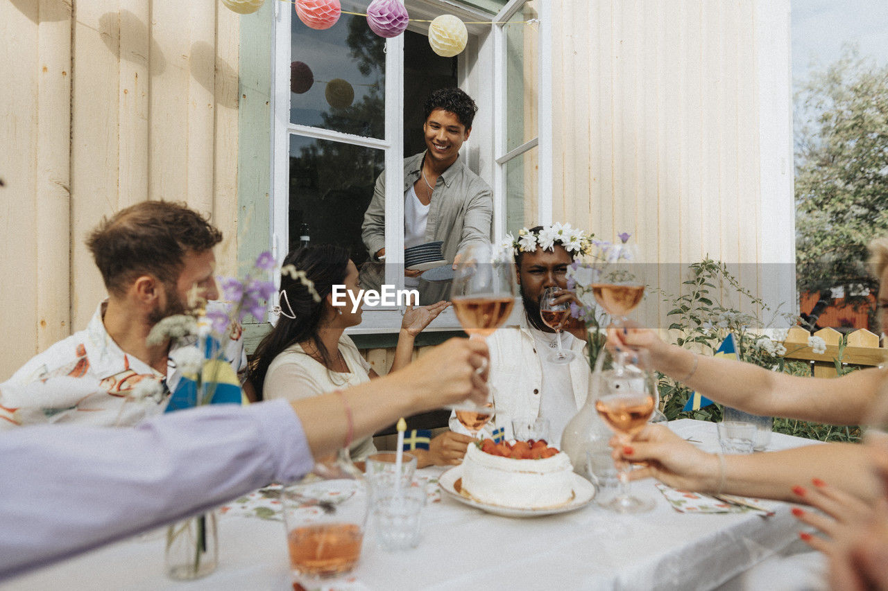 Smiling male and female friends celebrating party sitting outside cafe