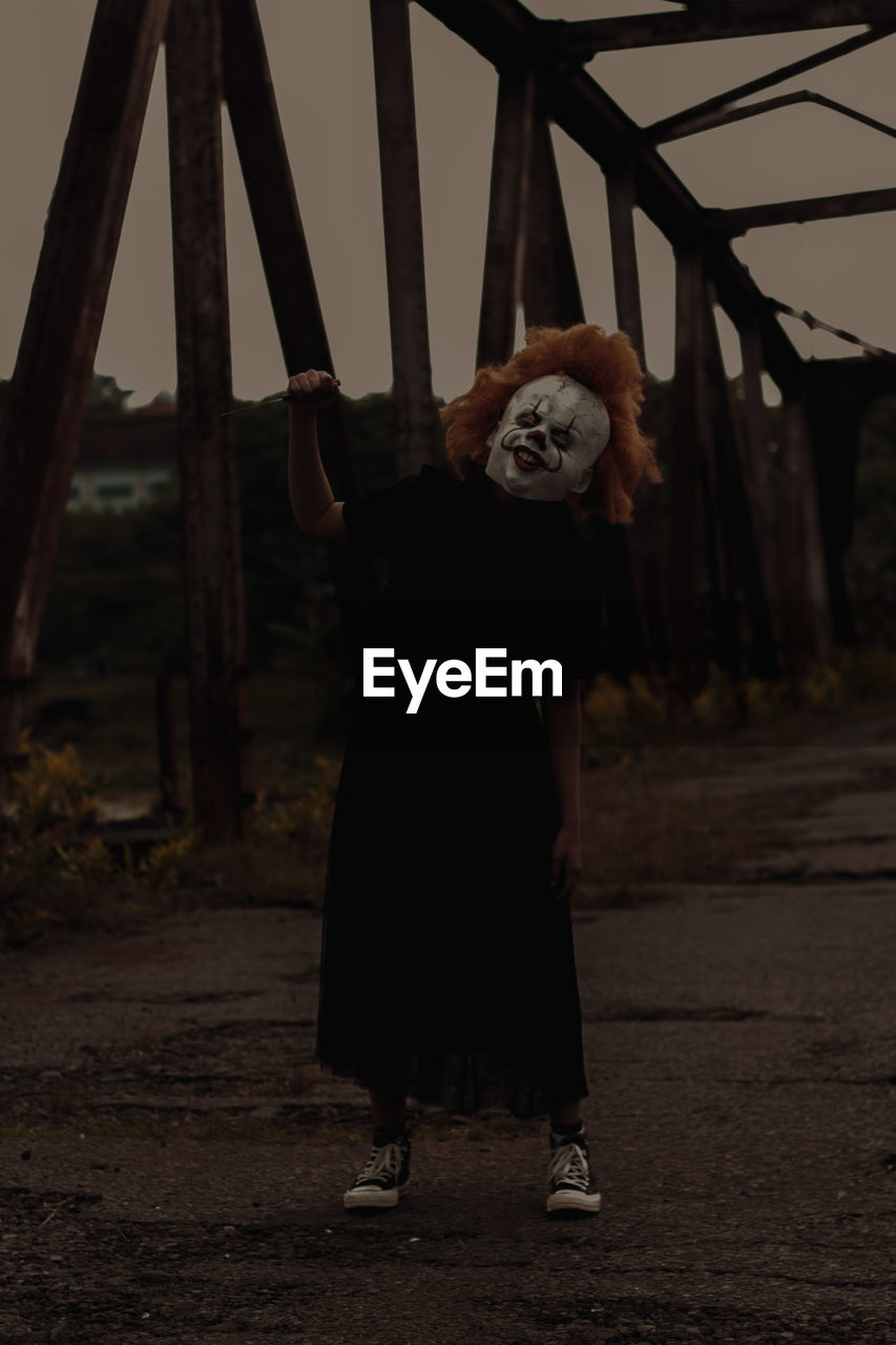 Young woman in mask standing on bridge