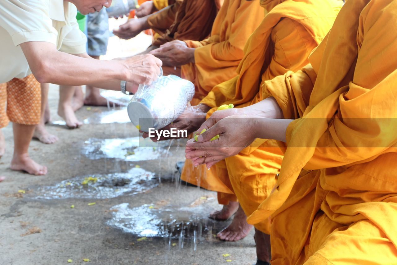 Man pouring water on monk hands outdoors