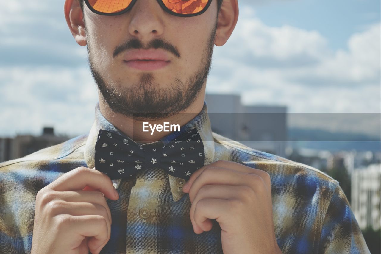 Midsection of young man adjusting bow tie