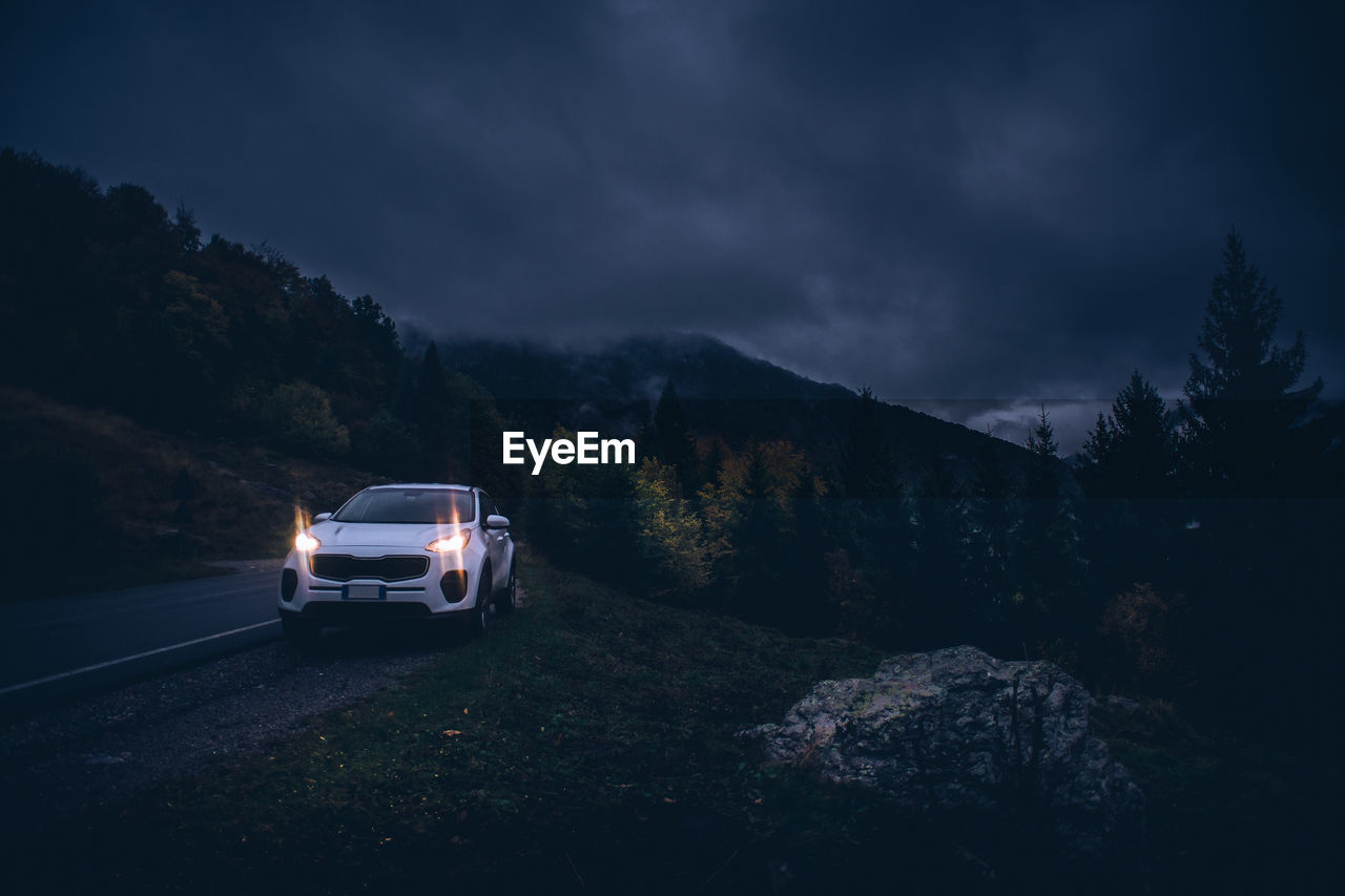 CAR ON ROAD AMIDST FIELD AGAINST SKY