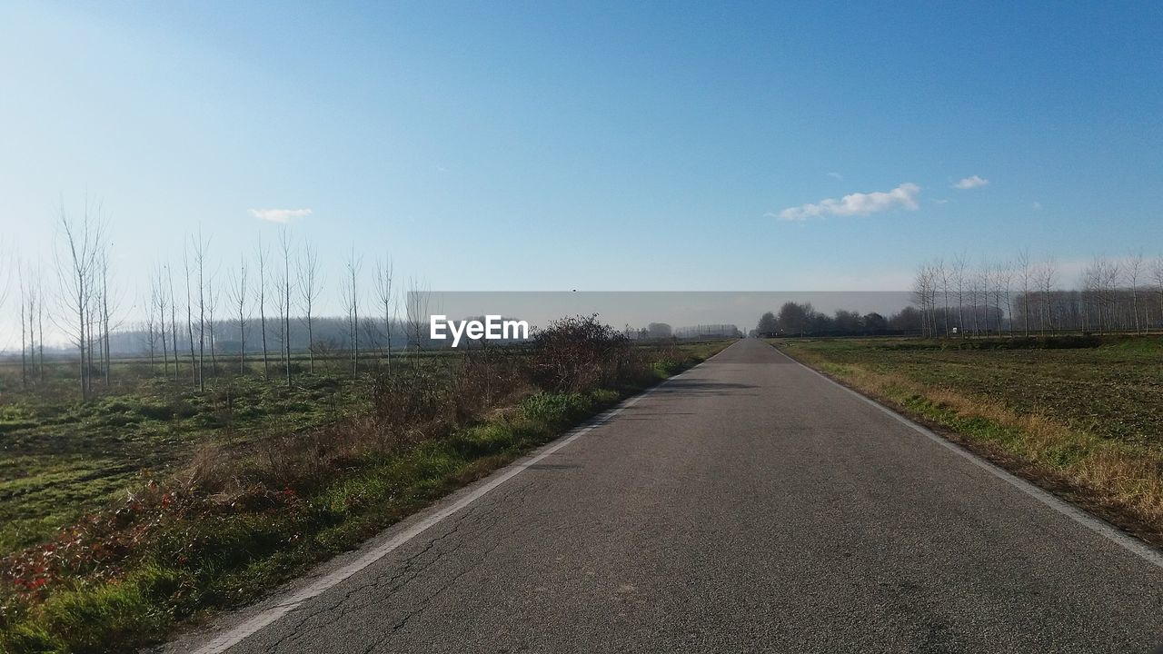 EMPTY ROAD AMIDST FIELD