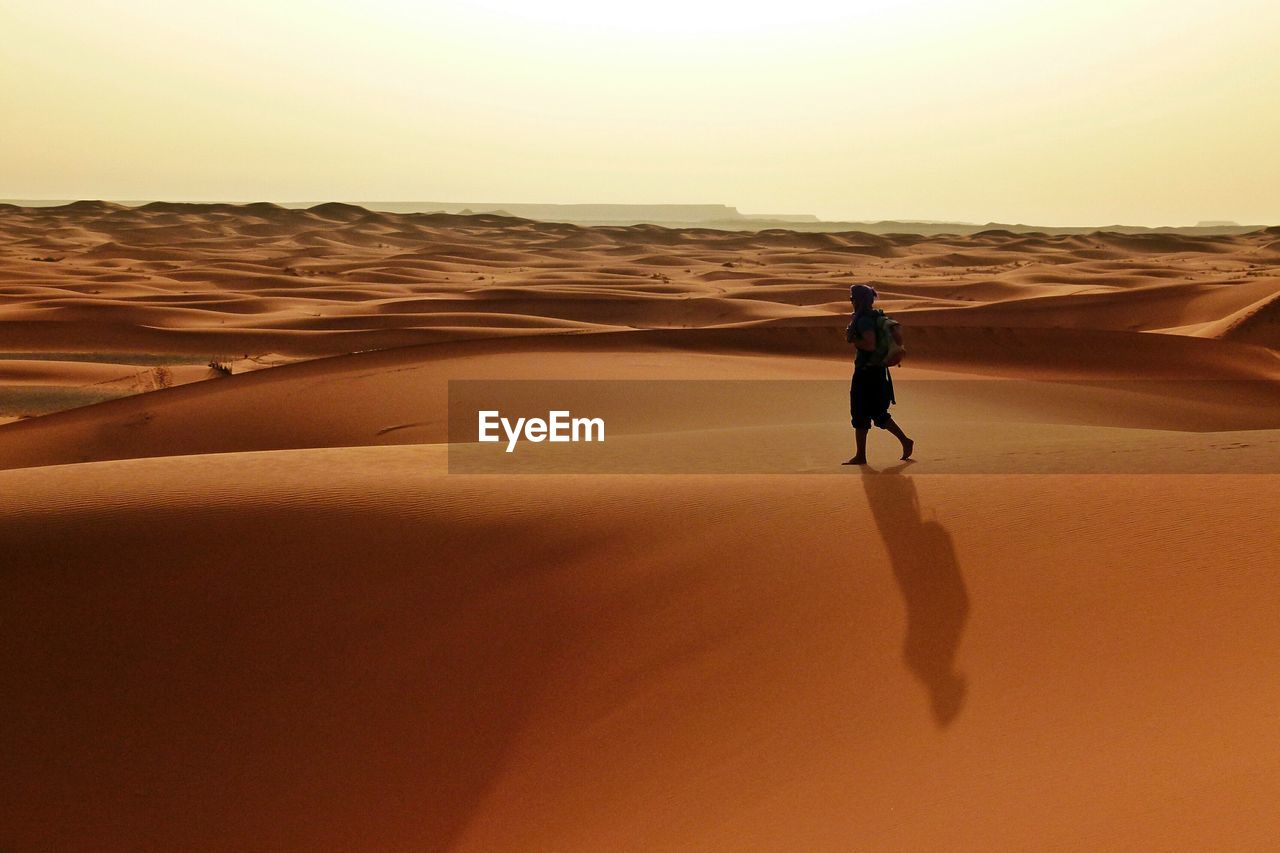 Full length of man walking on sand dunes at desert