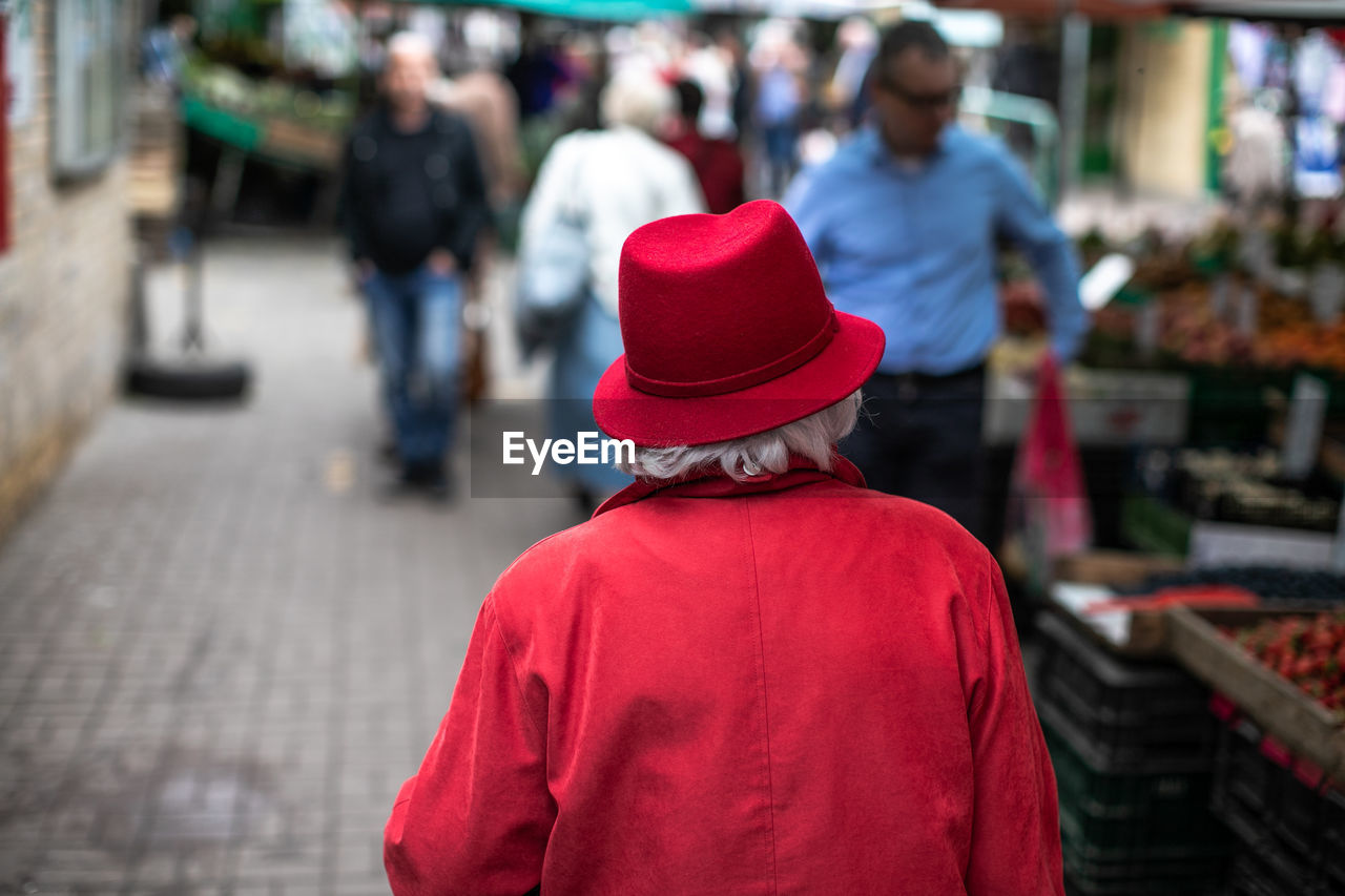 Rear view of woman wearing red clothing walking in market at city