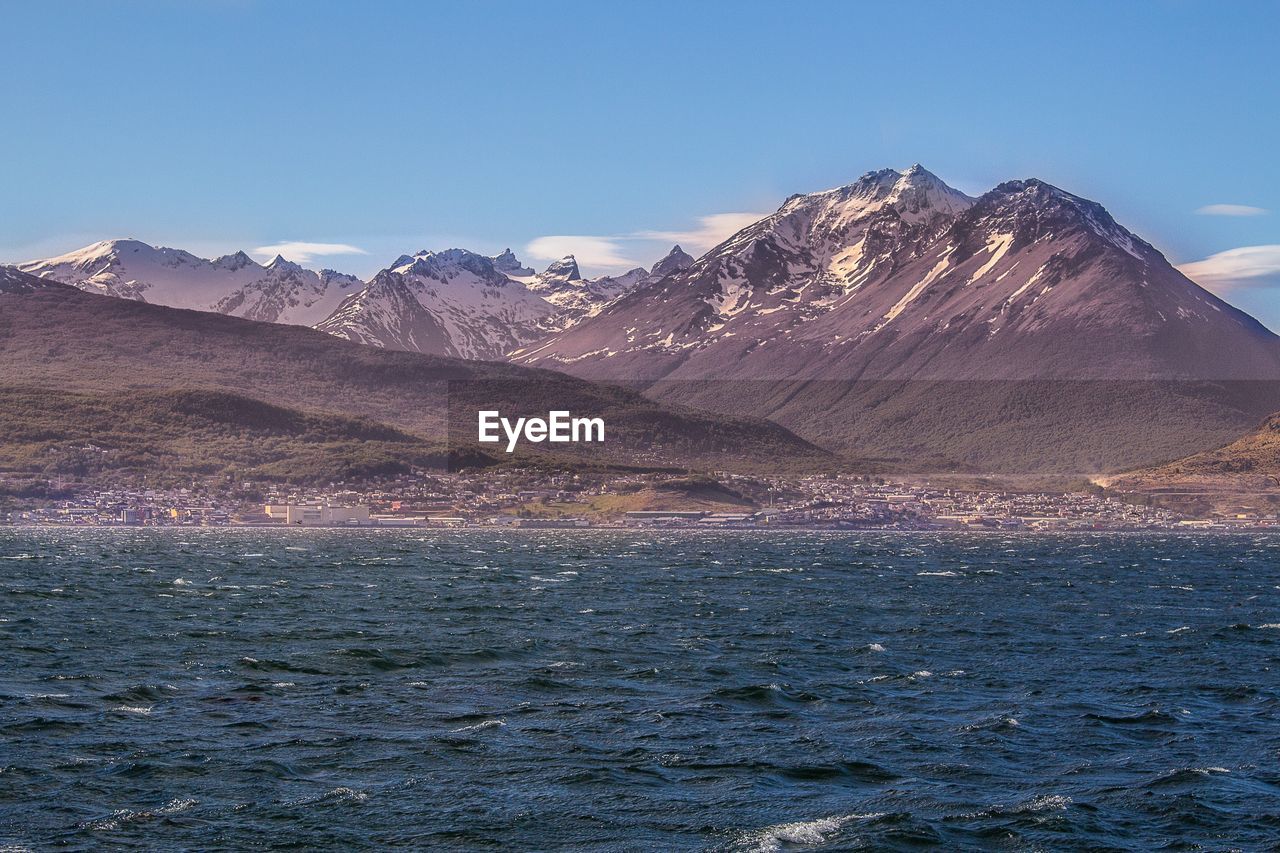 Scenic view of sea and mountains against blue sky