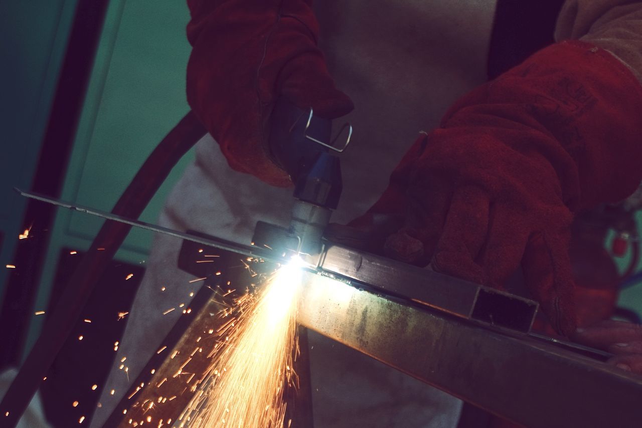 Midsection of craftsperson welding in workshop