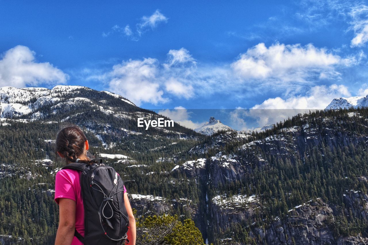 REAR VIEW OF WOMAN LOOKING AT MOUNTAINS