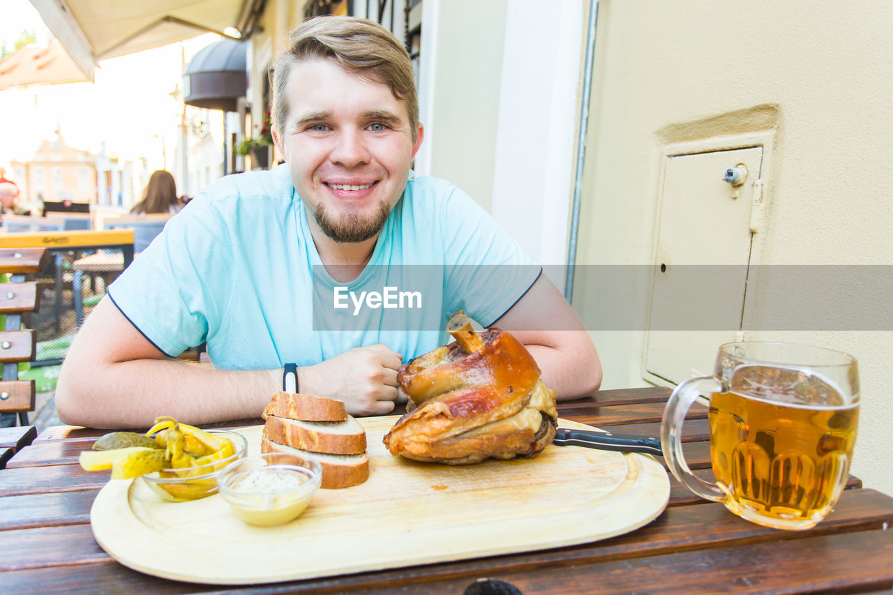 PORTRAIT OF SMILING MAN HAVING FOOD